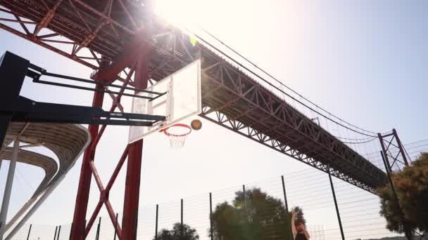 Muž Hodí Basketbal Koše Slunečného Dne Mostem Pozadí Pak Vyjde — Stock video
