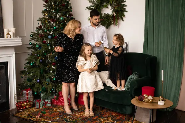 happy family playing with confetti on a background of Christmas trees in the interior of the house