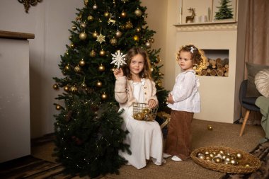 İki kardeş içeride Noel ağacının yanında oynuyorlar. Birlikte eğleniyorlar. Mutlu Noeller ve mutlu tatiller.