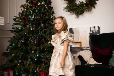 Kız Noel için süslenmiş ağacın yanında duruyor. Mutlu Noeller ve mutlu yıllar..