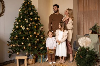 Noel ağacının yanında güzel dekore edilmiş bir aile Noel tatilinin tadını çıkarıyor..