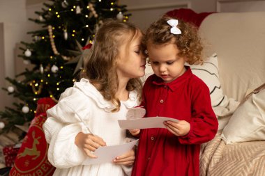 Mutlu Noeller ve mutlu tatiller. Noel ağacının yanında Noel Baba 'ya mektup yazan iki kız..