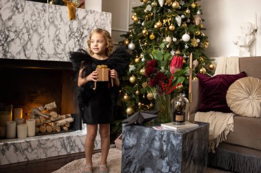 Elinde Noel hediyesi olan küçük bir kız. Noel, yeni yıl, kış ve tatil mevsimleri konsepti. Aile.