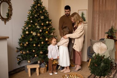 Noel ağacının yakınındaki aile Noel büyüsünün tadını çıkarıyor.