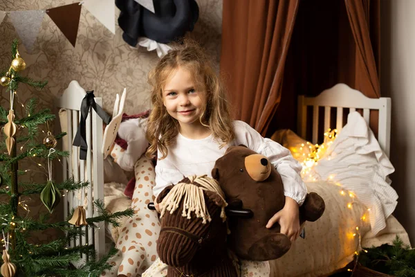 Çocuk Odasında Evde Oyuncak Hayvanlarla Yatakta Oturan Genç Bir Kız - Stok İmaj