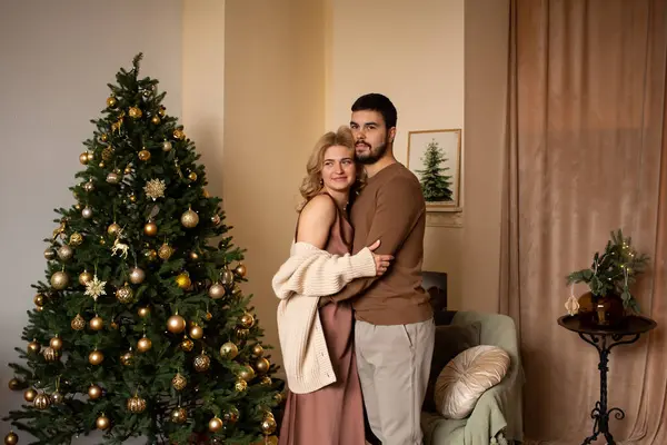 クリスマスツリーの隣に立って一緒に時間を楽しむ自宅で愛するカップル ストック写真