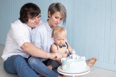 Mutlu bir aile. Anneciğim. Baba ve oğulları ilk doğum gününde pastasını yiyorlar yere oturup pasta partisini eziyorlar.