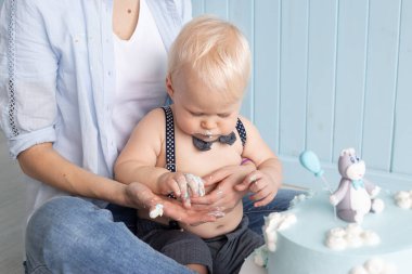 Anne ve oğlu ilk doğum gününde pastasını yiyorlar yere oturup pasta partisini eziyorlar.