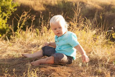 Bebek yazın doğada eğleniyor çimenlerde oturuyor gün batımında güneş ışınlarıyla