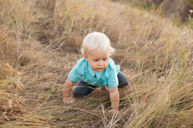 Yazın doğadaki çocuk gün batımında güneş ışınlarıyla çimenlerde oynuyor.