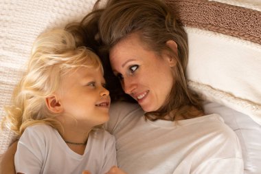 Mutlu gülümseyen anne portresi ve küçük oğlu evde yatakta uzanıp iyi vakit geçiriyorlar. Annelik, şefkat