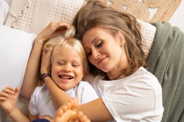 Anne ve küçük oğlu evde yatakta birbirlerine sarılıyorlar. Annelik, şefkat