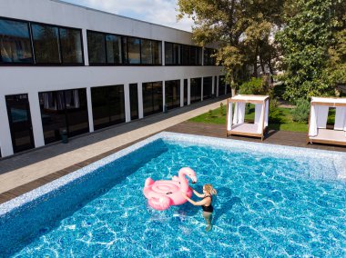 Flamingo havuzlu havuzda dinlenen bir kadının havadan görünüşü, insansız hava aracı manzarası. Yaz tatili