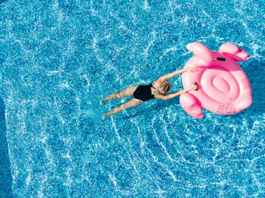Havuzda Flamingo arabası olan bir kadın. Yaz tatilleri, lüks otellerde yaz tatilleri. Hava aracı görünümü