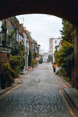 Mews Notting Hill 'de bir kemerden geçiyor, bir bayan uzaklaşıyor.