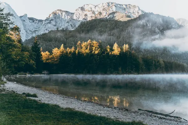 A majestic mountain landscape in the Austrian Alps. Misty morning over Langbathseen lake.