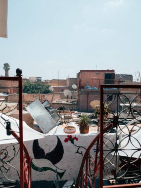 A sunny day in Marrakech reveals a colorful rooftop view filled with satellite dishes, eclectic decor, and the charm of local architecture against a clear blue sky. clipart