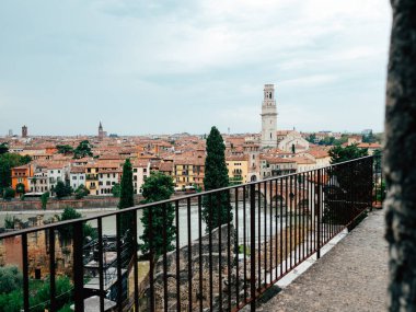 Panoramik bir manzara Verona 'nın büyüleyici mimarisini gözler önüne seriyor. Terracotta çatıları ve şafak vakti bulutlu bir gökyüzünün altında çarpıcı bir çan kulesi..