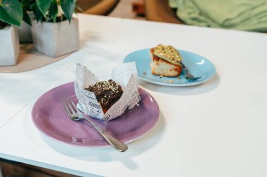 Sıcak bir kafe masasında renkli tabaklarda iki enfes pişmiş ikram sergileniyor. Bir tatlıda fındık var, diğerinde ise altın sarısı, öğleden sonra tatili için mükemmel..