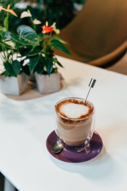 Canlı bir vejetaryen kirli çay, yemyeşil ile çevrili küçük bir kafe masasında renkli bir tabağın üzerinde cam bir fincanın içinde oturur. Ortam rahatlatıcı bir ortam..