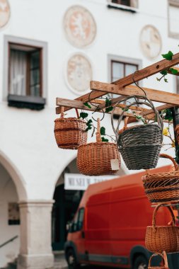 Borsa ortamında ahşap bir rafta asılı renkli örülmüş sepetler. Mimarinin ilgi çekici bir arka planı ve canlı bir atmosfer yaratan bir teslimat minibüsüyle çevrilidirler..