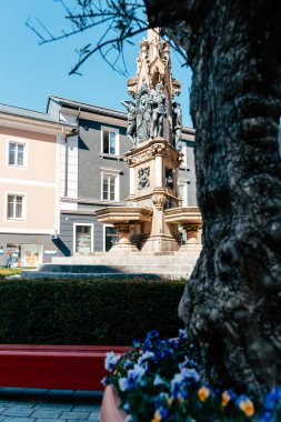 Bad Ischl 'de güzel bir gün, ön planda canlı çiçekler ve arka planda önemli bir tarihi eser. Ziyaretçiler açık gökyüzünün ve bölgenin büyüleyici mimarisinin tadını çıkarıyorlar..