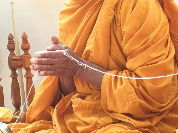 Keşişler ellerini birleştirip kutsal ipi tutarlar..