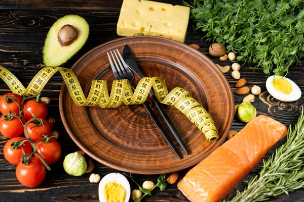 Keto diyeti. Faydalı ürünler masada. Boş bir tabakta, bıçak ve çatal mezuranın altında yatıyor. Uygun beslenme