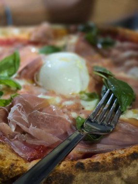 Jambonlu ve çatallı lezzetli pizzanın yakın görüntüsü 