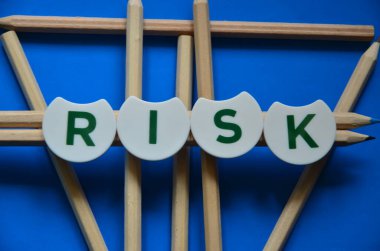 Mavi arkaplanı olan tahta küplerde risk metni.