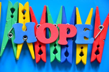 Umut kelimesinin üzerinde renkli mandallar.