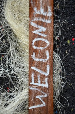 Hoş geldin kelimesi ahşap bir arka planda halatla yazılmış.