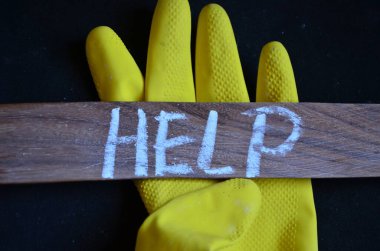 Yardım işareti var. Bir şey ya da birine ahşap arka planda duran yapışkan not kağıdına bir şey yazması için iş fotoğrafı gösteriliyor.