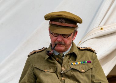 İkinci Dünya Savaşı 'ndan kalma klasik askeri üniformalı bir adam dışarıda oturmuş kitap okuyor.