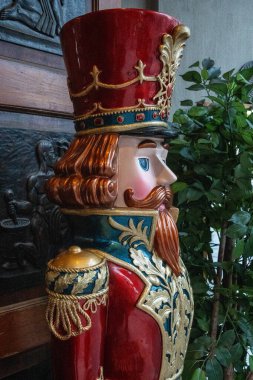 Noel süsleriyle çevrili kırmızı ceketli neşeli bir asker, bayram neşesi ekliyor..