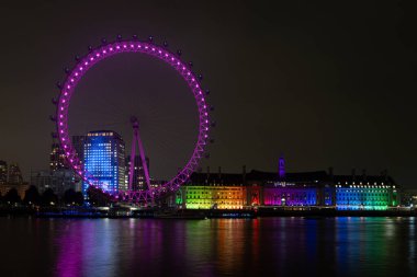 İngiltere, Londra 24 Kasım: Londra Milenyum Çarkıfeleği ve Belediye Binası Thames Nehri üzerindeki yansımalarla gece aydınlandı