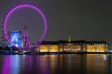İngiltere, Londra 24 Kasım: Londra Milenyum Çarkıfeleği ve Belediye Binası Thames Nehri üzerindeki yansımalarla gece aydınlandı