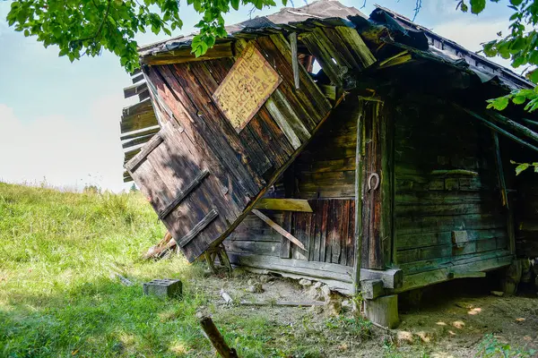 Brasov, Romanya - Ağustos 2019: Eski, eğik bir ahşap çoban kulübesi, önemli bir bakım ve hava durumu gösteriyor.