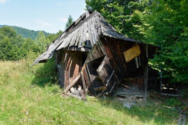Brasov, Romanya - Ağustos 2019: Eski, eğik bir ahşap çoban kulübesi, önemli bir bakım ve hava durumu gösteriyor.