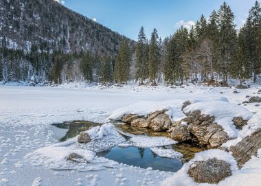 Kuzey İtalya 'daki Julian Alpleri' nde kayalar ve karla kaplı donmuş bir göl.