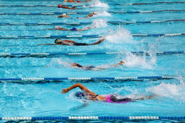 Sporcular yüzme havuzunda yarışıyorlar.