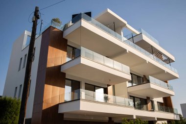 Modern Mimari Marvel: Pürüzsüz Balkonları ve Çağdaş Tasarım Özellikleri Açık Mavi Gökyüzüne Karşı olan Şık Çok Katlı Bina