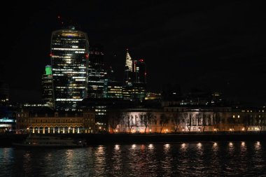 Bishopsgate 'deki Londra gökdelenlerinin gece manzarası, Thames nehri ön planda..