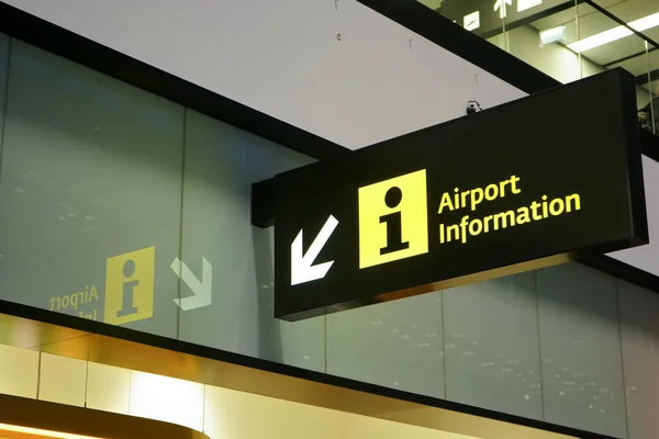 Illuminated Airport information sign with arrow pointing to side, closeup detail.