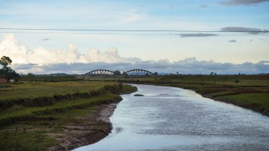 Railway bridge over small river near Ambatolampy, Madagascar, green grass and trees around. There is only small number of railroads on whole island.