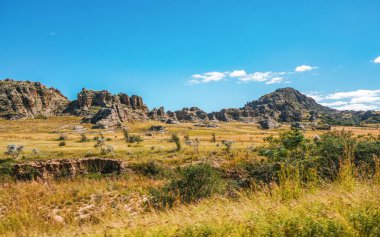 Afrika ovalarında yetişen alçak çimler, arka planda küçük kayalık dağlar - Isalo Ulusal Parkı, Madagaskar 'daki tipik manzara.