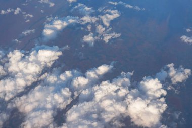 Öğleden sonra güneşiyle aydınlanan yumuşak gökyüzü bulutları üzerinde uçan ticari uçaklardan görüldüğü gibi.