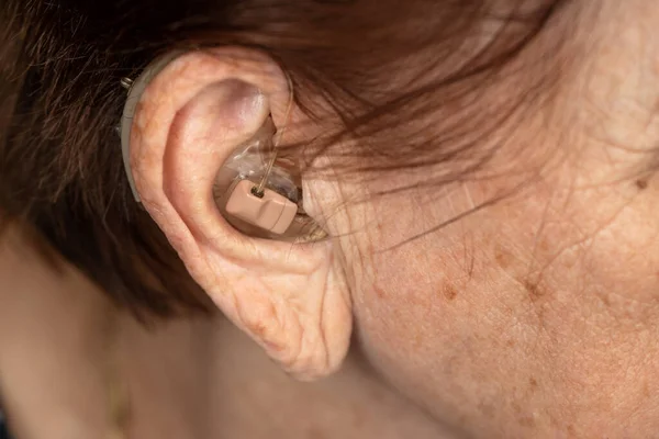 Hearing aid device in senior woman ear - closeup photo