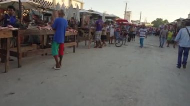 Toliara, Madagaskar - 01 Mayıs 2019: Akşamları tipik orta büyüklükteki bir kasaba caddesinde yürümek, her iki tarafta market tezgahları, Malagasy 'li insanlar yürüyor, bazıları motosiklet veya scooter kullanıyor