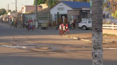 Toliara, Madagaskar - 30 Nisan 2019: Ana yoldaki tipik akşam manzarası, insanlar yürüyor, bisiklet rikşovu ve motosiklet geçiyor, yan taraftaki dükkanlar